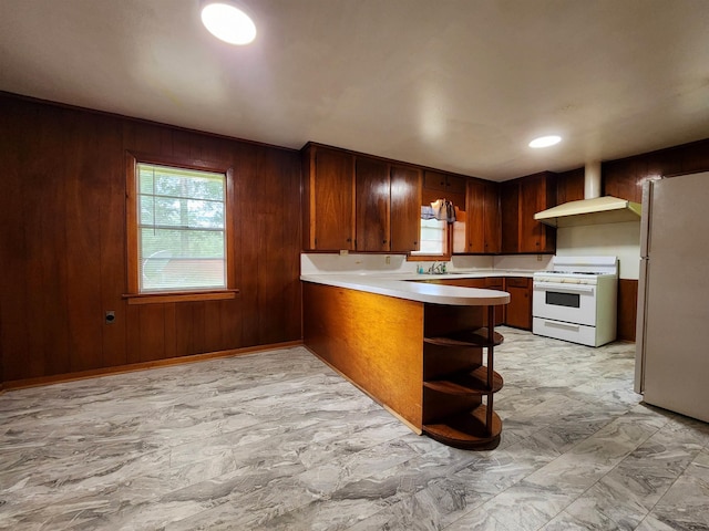 kitchen with marble finish floor, white appliances, light countertops, and wood walls