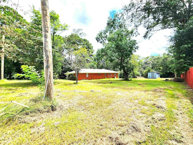 view of yard featuring a storage unit, an outbuilding, and fence