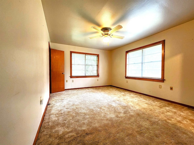 carpeted empty room featuring baseboards and a ceiling fan