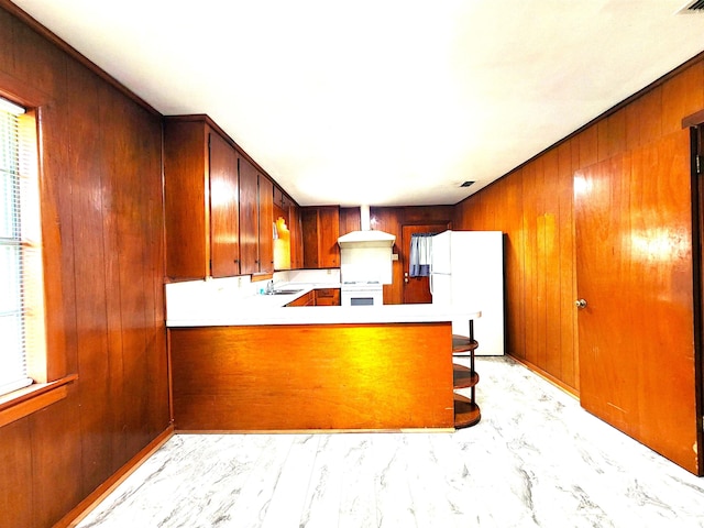 kitchen featuring oven, marble finish floor, a sink, freestanding refrigerator, and wood walls