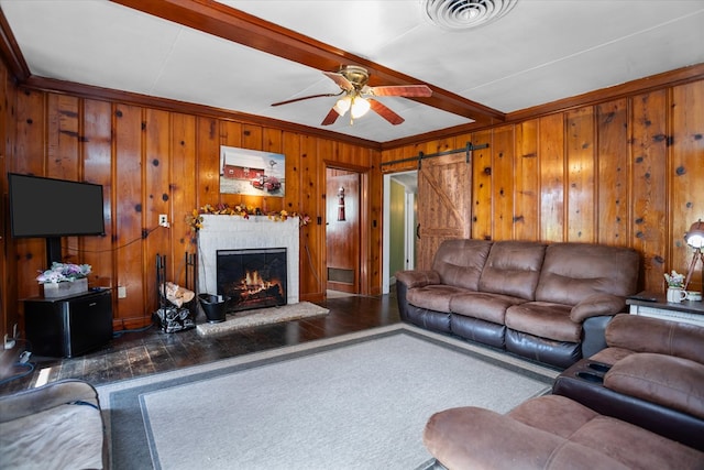 505 S Home St, Corrigan, TX 75939 - living room featuring beamed ceiling, a warm lit fireplace, a ceiling fan, wood walls, and crown molding