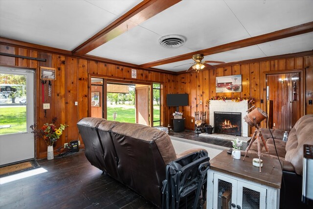 505 S Home St, Corrigan, TX 75939 - living area featuring beamed ceiling, a warm lit fireplace, dark wood-style flooring, ceiling fan, and wooden walls