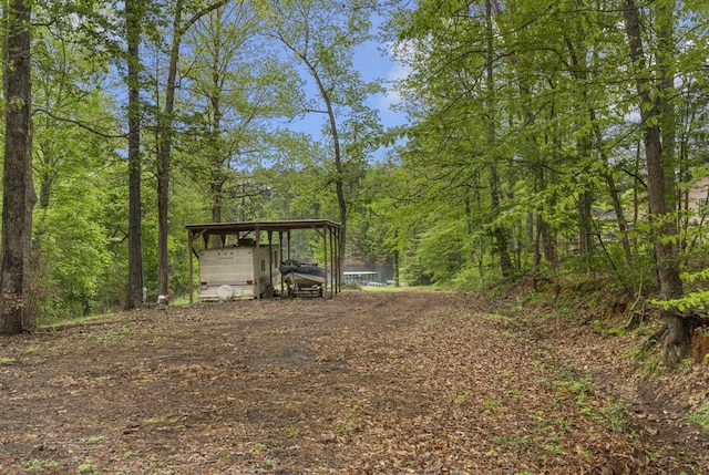 211 Winfree Dr, Hemphill, TX 75948 - view of yard with driveway, a wooded view, an outdoor structure, and a carport