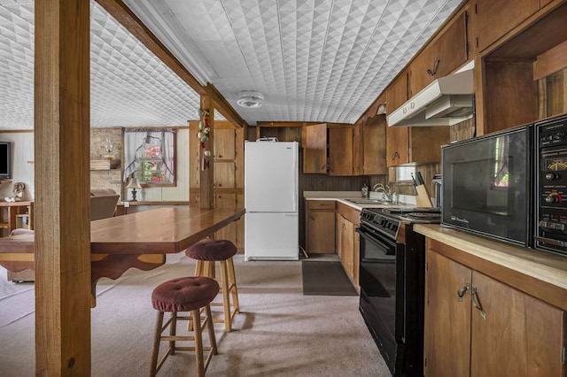 211 Winfree Dr, Hemphill, TX 75948 - kitchen with light countertops, light colored carpet, under cabinet range hood, a sink, and black appliances
