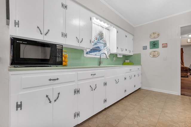 kitchen with white cabinets, decorative backsplash, ornamental molding, and sink