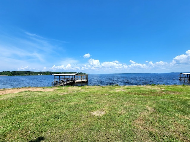 dock area with a lawn and a water view