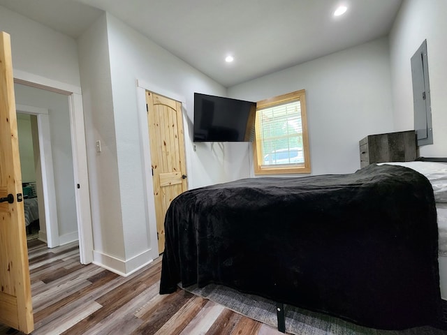 bedroom featuring recessed lighting, electric panel, wood finished floors, and baseboards