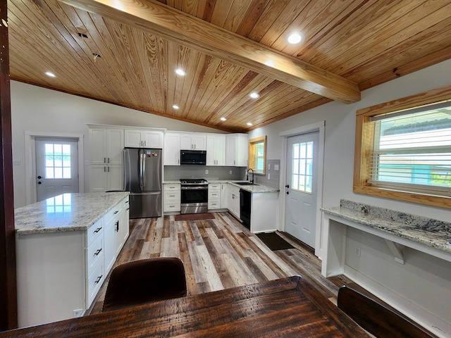 kitchen featuring white cabinetry, a sink, stainless steel appliances, wooden ceiling, and vaulted ceiling with beams