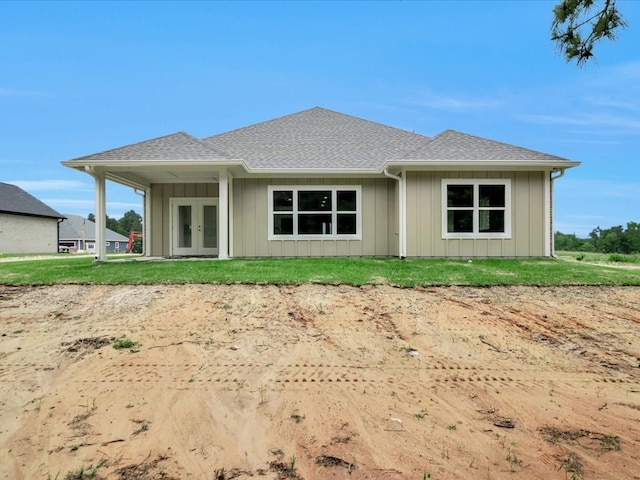 back of property with board and batten siding, a shingled roof, french doors, and a lawn