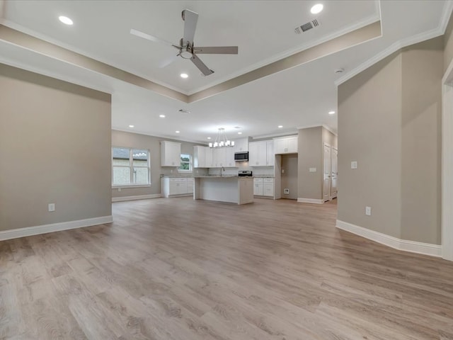 unfurnished living room featuring visible vents, baseboards, ceiling fan with notable chandelier, and ornamental molding