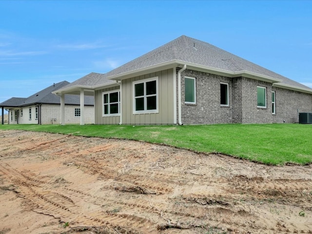 back of property featuring cooling unit, board and batten siding, brick siding, and a lawn