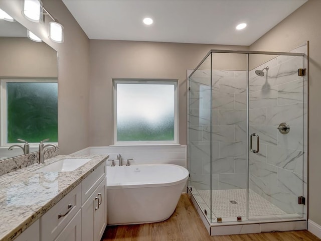 full bath with vanity, a stall shower, wood finished floors, and a freestanding tub
