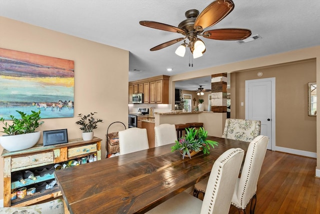 dining space featuring dark wood-type flooring, a textured ceiling, and ceiling fan