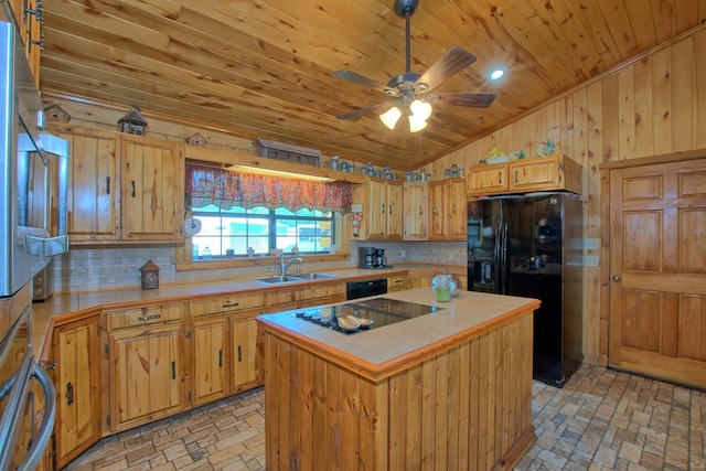 kitchen with sink, tasteful backsplash, wood walls, a kitchen island, and black appliances