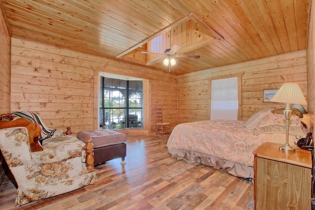 bedroom featuring ceiling fan, hardwood / wood-style floors, wooden ceiling, and wood walls