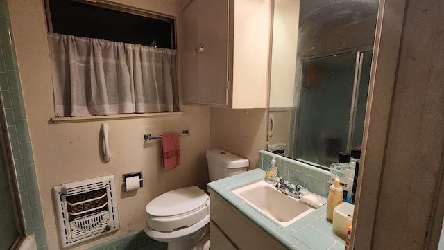 bathroom with backsplash, vanity, heating unit, toilet, and a shower with shower door