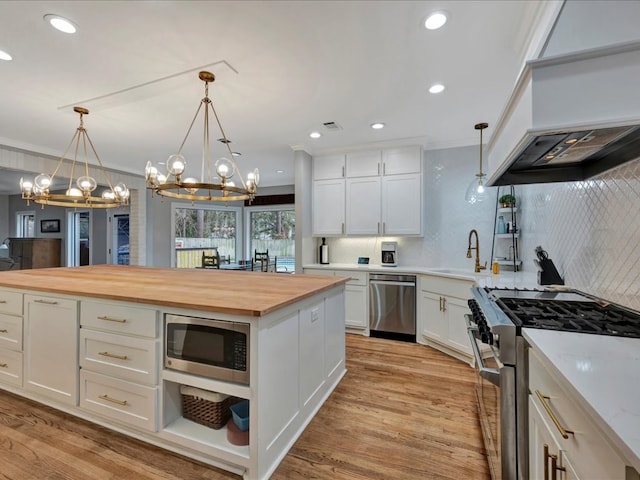 kitchen with tasteful backsplash, white cabinetry, stainless steel appliances, and wood counters