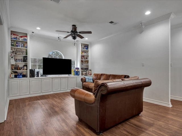 living room with built in shelves, ceiling fan, and crown molding