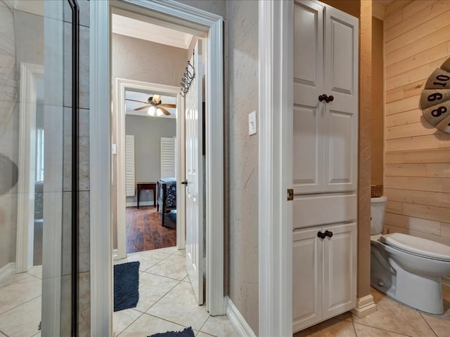 bathroom featuring tile patterned floors, ceiling fan, wood walls, and toilet