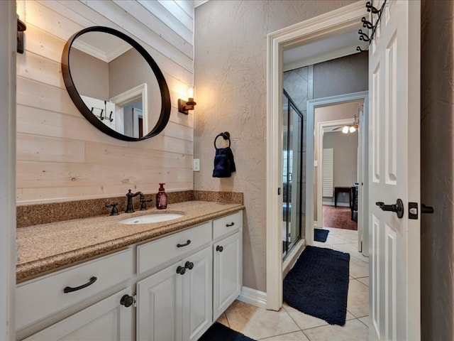 bathroom featuring vanity, wood walls, tile patterned flooring, ornamental molding, and a shower with shower door