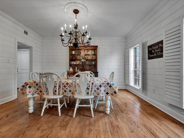 dining room with a notable chandelier, light hardwood / wood-style floors, and ornamental molding