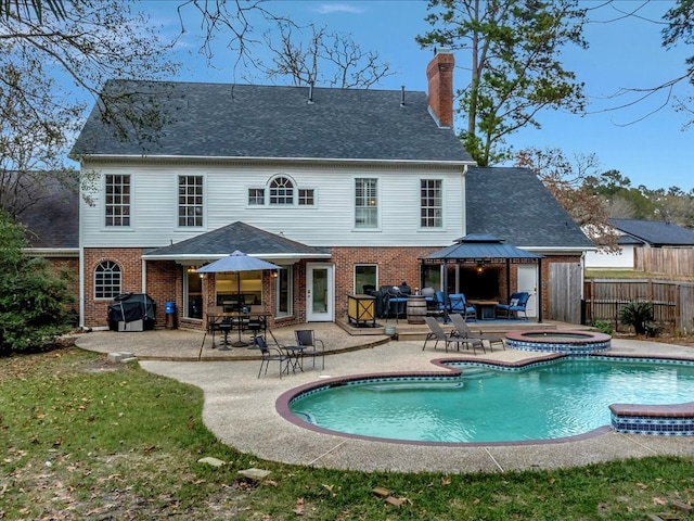 back of house with a gazebo, a swimming pool with hot tub, and a patio