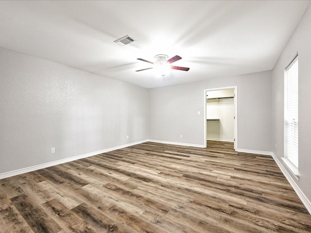 empty room featuring visible vents, ceiling fan, baseboards, and wood finished floors