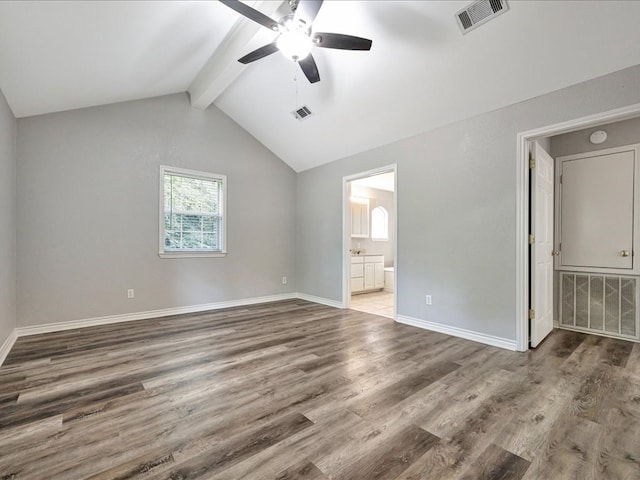 unfurnished bedroom featuring wood-type flooring, connected bathroom, ceiling fan, and vaulted ceiling with beams