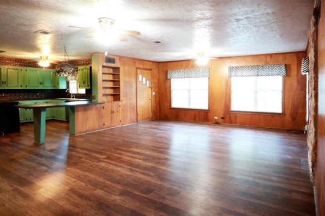 unfurnished living room featuring wood walls, dark hardwood / wood-style flooring, and a textured ceiling