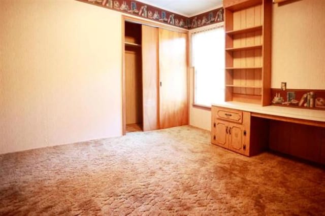 unfurnished office with built in desk and light colored carpet