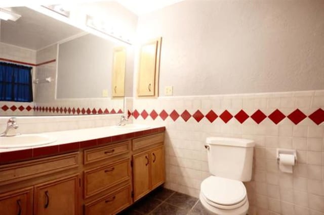 bathroom with tile patterned flooring, vanity, toilet, and tile walls