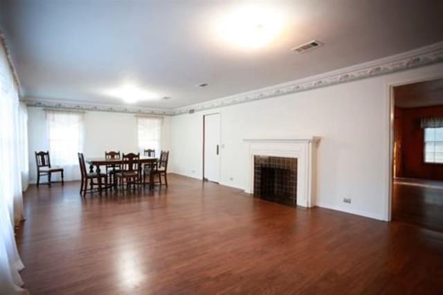 dining space featuring crown molding, a fireplace, and dark hardwood / wood-style floors