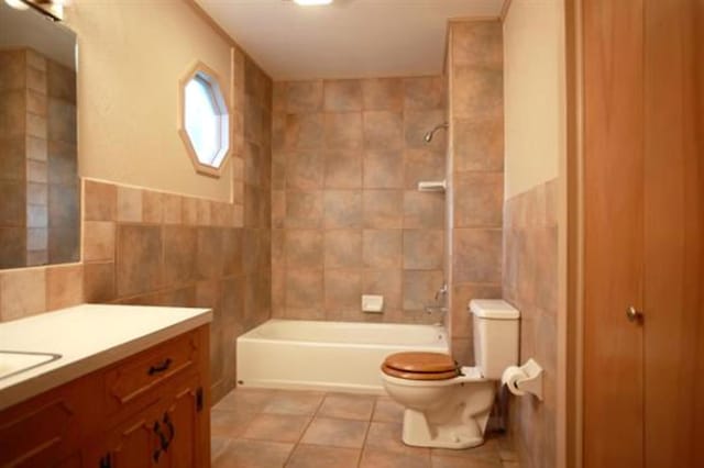 full bathroom featuring tile patterned flooring, toilet, shower / washtub combination, vanity, and tile walls