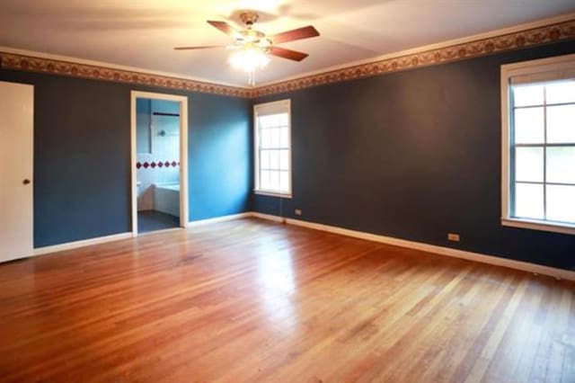 unfurnished bedroom featuring ceiling fan, wood-type flooring, crown molding, and ensuite bath