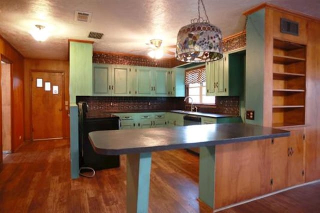 kitchen featuring backsplash, sink, kitchen peninsula, and dark wood-type flooring