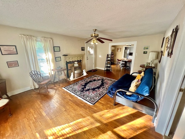 living room with ceiling fan, wood-type flooring, and a textured ceiling