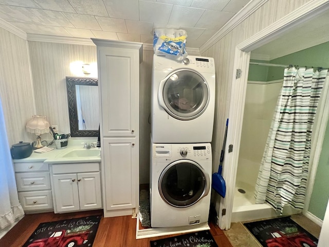 clothes washing area featuring dark hardwood / wood-style flooring, stacked washing maching and dryer, ornamental molding, and sink