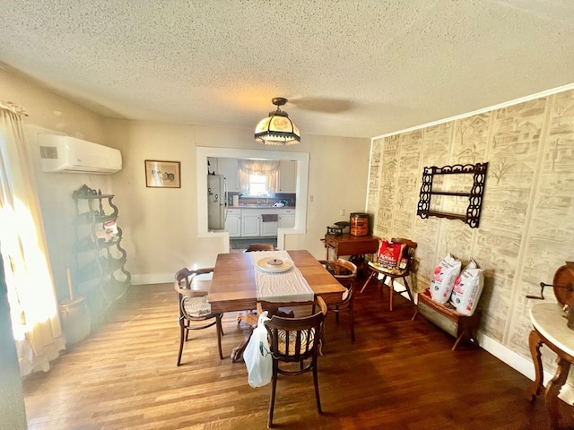 dining room featuring wood-type flooring, a textured ceiling, and an AC wall unit