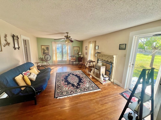 living room with plenty of natural light, ceiling fan, wood-type flooring, and a textured ceiling