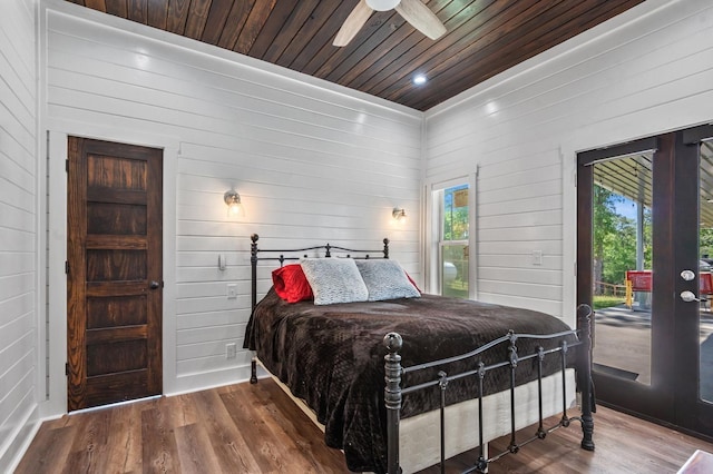 bedroom with hardwood / wood-style flooring, ceiling fan, and wood walls