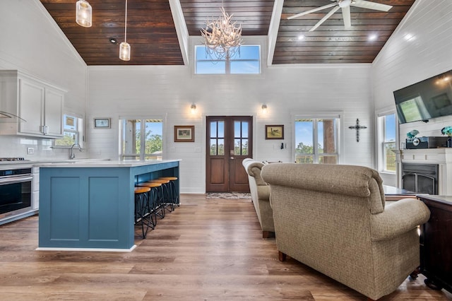 living room featuring plenty of natural light, high vaulted ceiling, wood ceiling, and light hardwood / wood-style floors