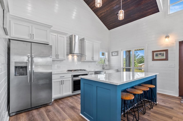 kitchen featuring white cabinetry, wall chimney range hood, high vaulted ceiling, a kitchen island, and appliances with stainless steel finishes