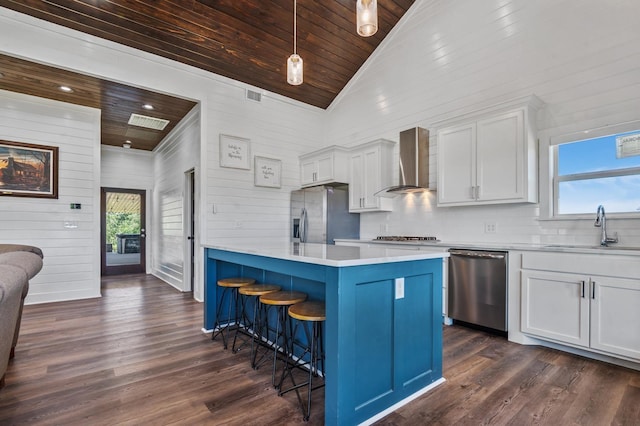 kitchen featuring appliances with stainless steel finishes, a wealth of natural light, wall chimney exhaust hood, sink, and a center island