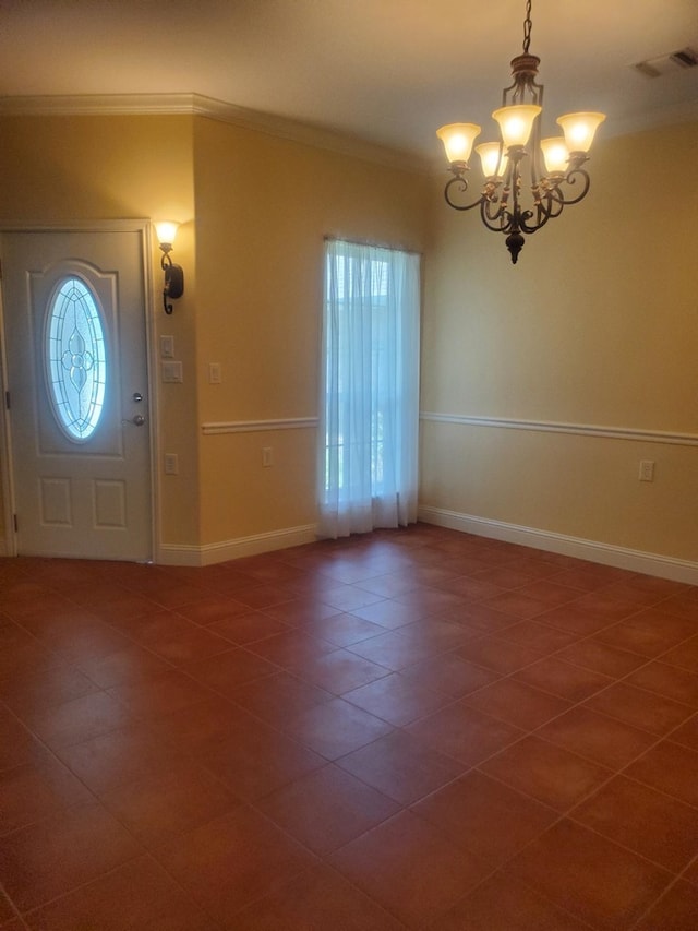 foyer featuring crown molding, dark tile patterned floors, and a chandelier