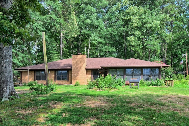 view of front of property featuring a sunroom and a front lawn