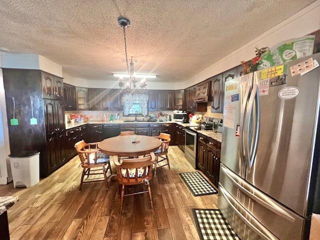 kitchen with dark brown cabinets, an inviting chandelier, stainless steel appliances, and hardwood / wood-style flooring