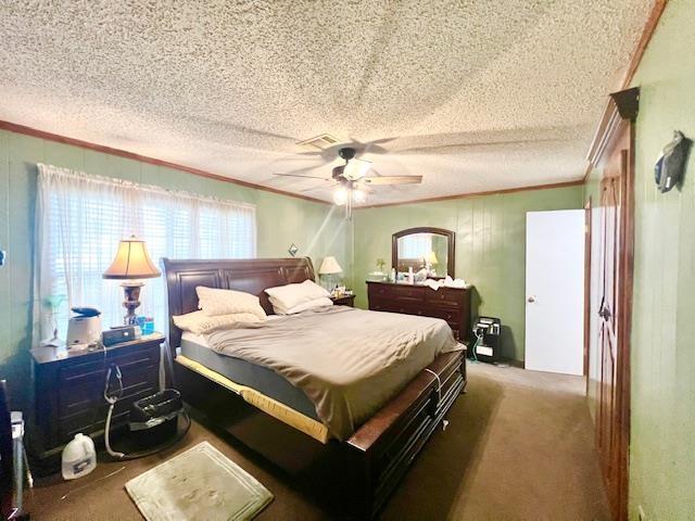 bedroom with dark colored carpet, a textured ceiling, ceiling fan, and ornamental molding