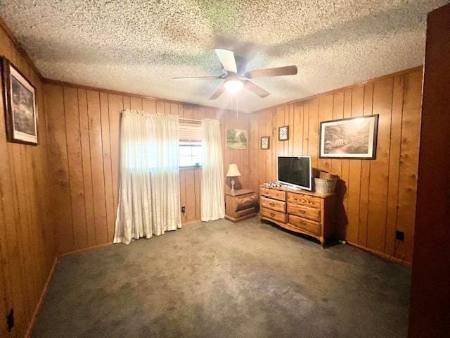 bedroom with dark colored carpet, a textured ceiling, ceiling fan, and wood walls