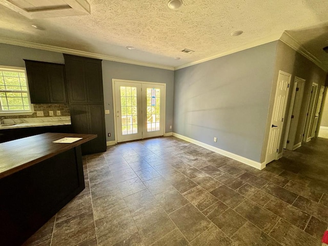 2505 County Road 4420, Spurger, TX 77660 - unfurnished dining area with healthy amount of natural light, crown molding, baseboards, a sink, and french doors