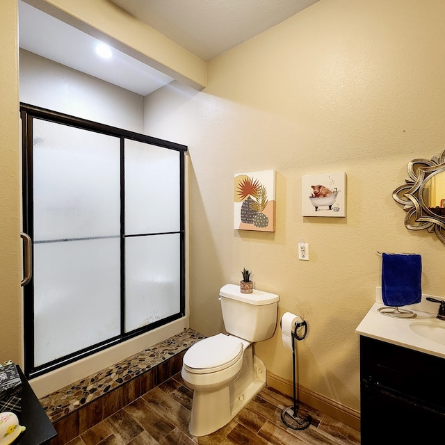 bathroom with a shower stall, wood finished floors, toilet, vanity, and baseboards
